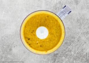 Top view of a blender with thick, orange-yellow soup or sauce mixture on a textured gray surface, inspired by Not a Classic Boring Turkey: Citrus-Garlic Chipotle Thanksgiving Turkey Recipe.