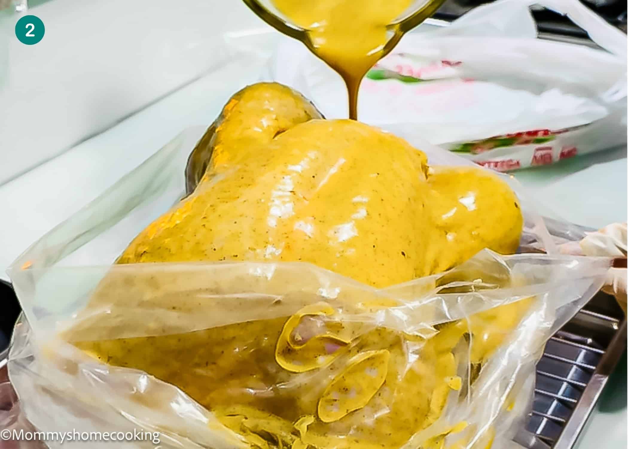 A whole raw chicken in a plastic bag is being coated with a vibrant yellow Citrus-Garlic Chipotle marinade, poured from a bowl—perfect inspiration for your Thanksgiving Turkey Recipe.