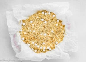 A baking dish lined with parchment paper, filled with uncooked rice and ceramic baking beads for blind baking a pie crust—perfect preparation for an Eggless Classic Chess Pie Recipe.