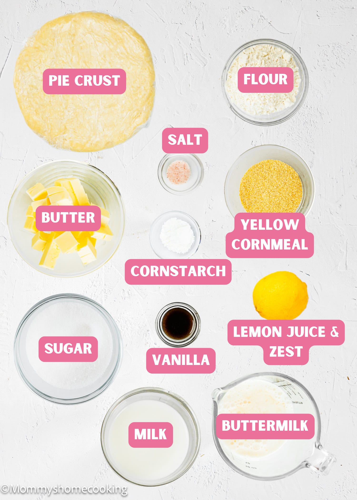 Top-down view of labeled baking ingredients in bowls for an Eggless Classic Chess Pie Recipe, including pie crust, flour, butter, salt, yellow cornmeal, cornstarch, sugar, vanilla, lemon juice and zest, milk, and buttermilk.