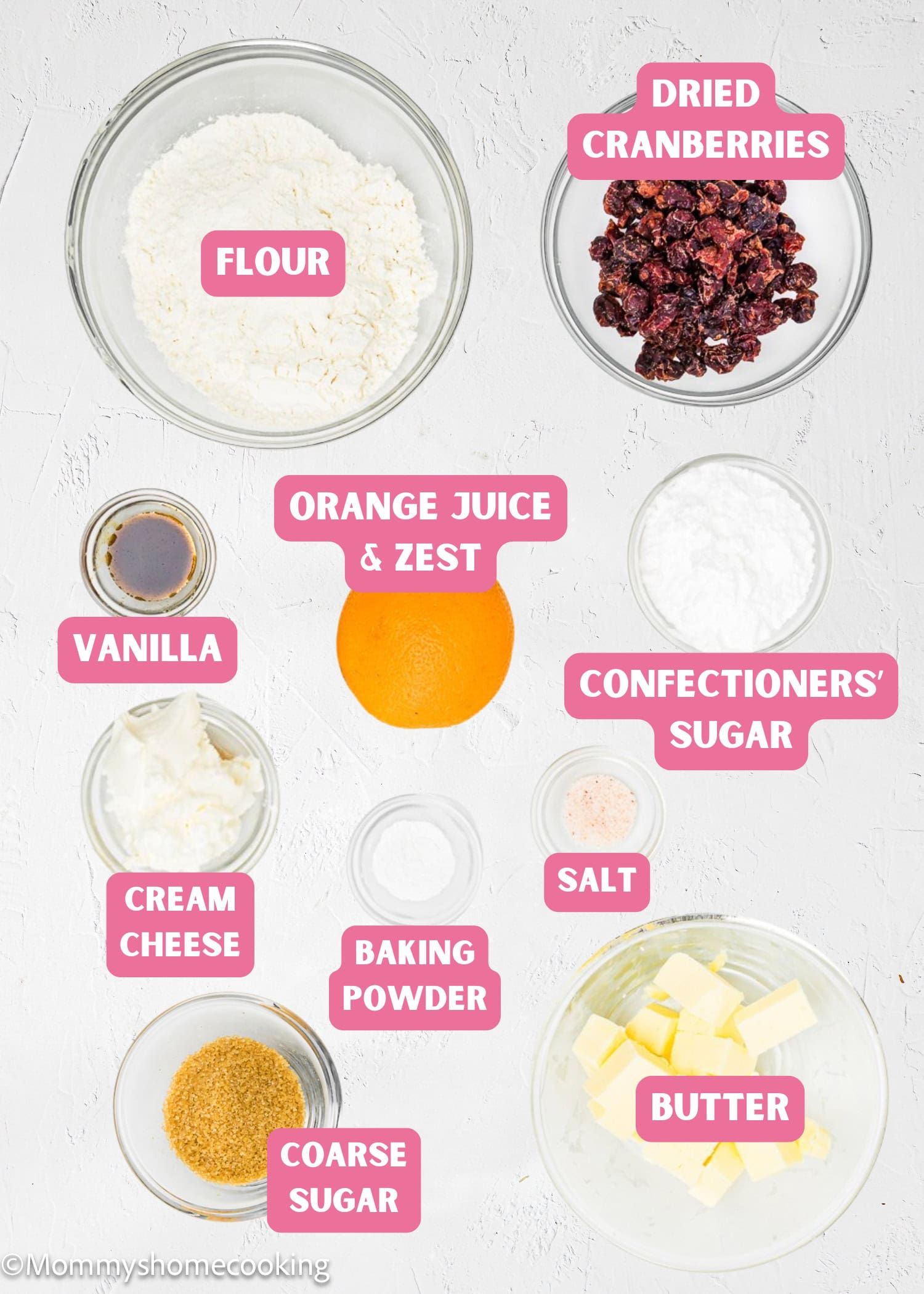 Ingredients for Eggless Cranberry Orange Icebox Cookies, including flour, dried cranberries, orange, vanilla, confectioners' sugar, cream cheese, baking powder, salt, coarse sugar, and butter—each labeled in bowls.