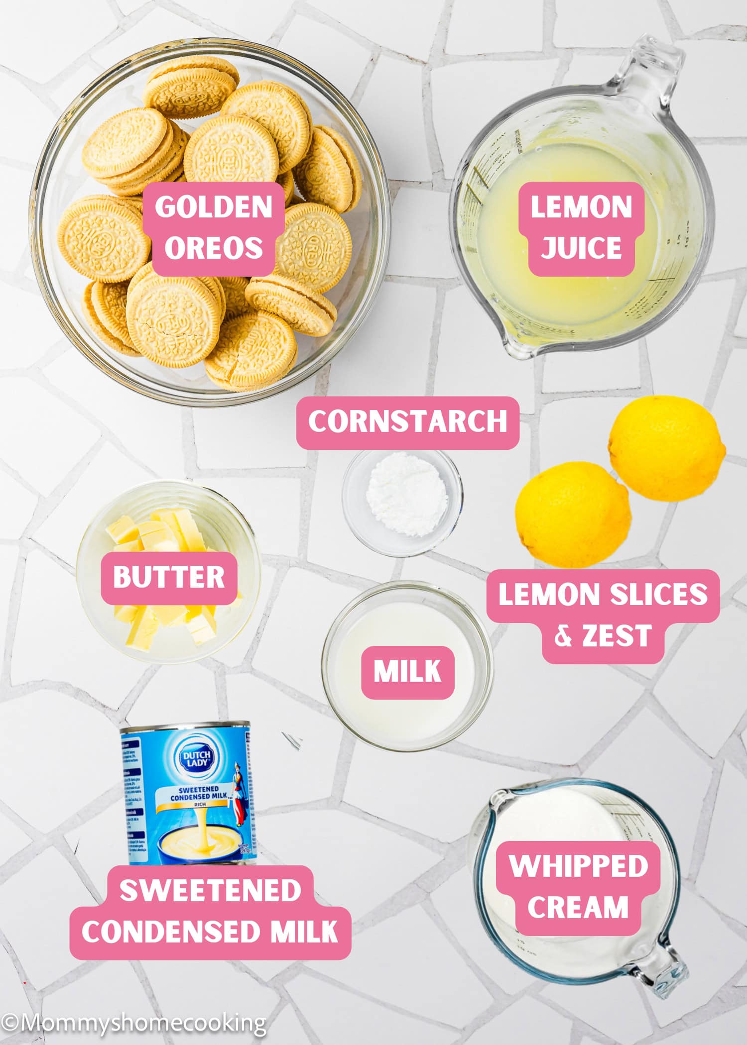Top-down view of ingredients for an Eggless Creamy Lemon Pie, including Golden Oreos, lemon juice, cornstarch, butter, milk, lemon slices and zest, sweetened condensed milk, and whipped cream.