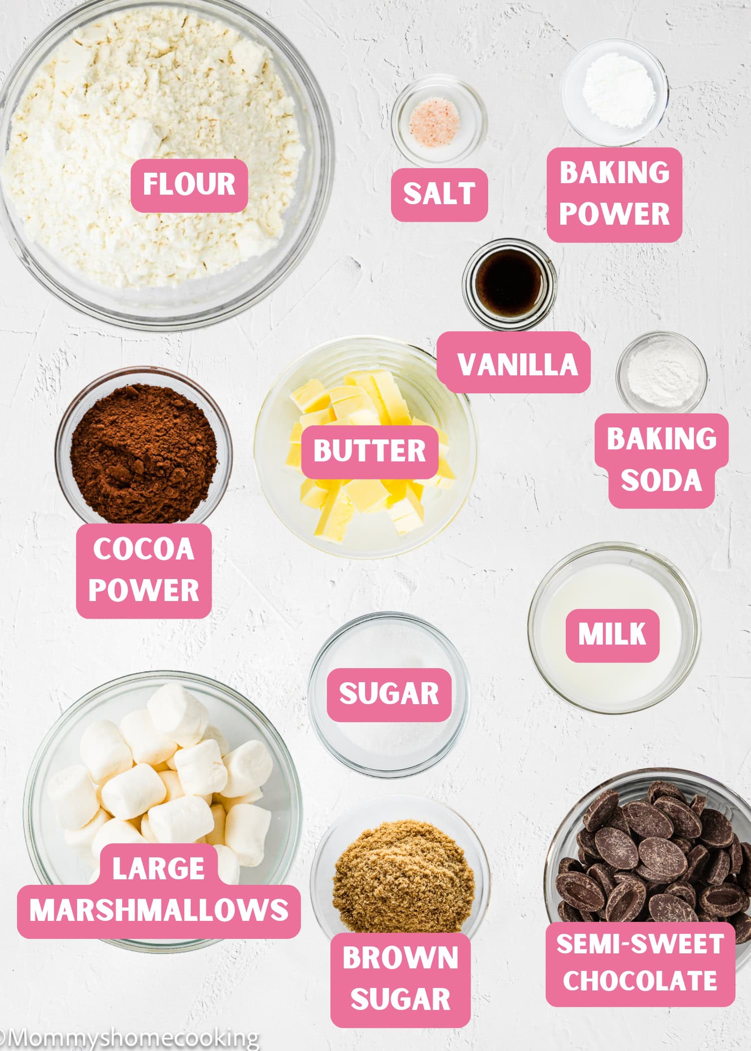 Top-down view of labeled baking ingredients for Eggless Hot Chocolate Cookies, including flour, salt, baking powder, vanilla, cocoa powder, butter, milk, sugars, large marshmallows, and semi-sweet chocolate.