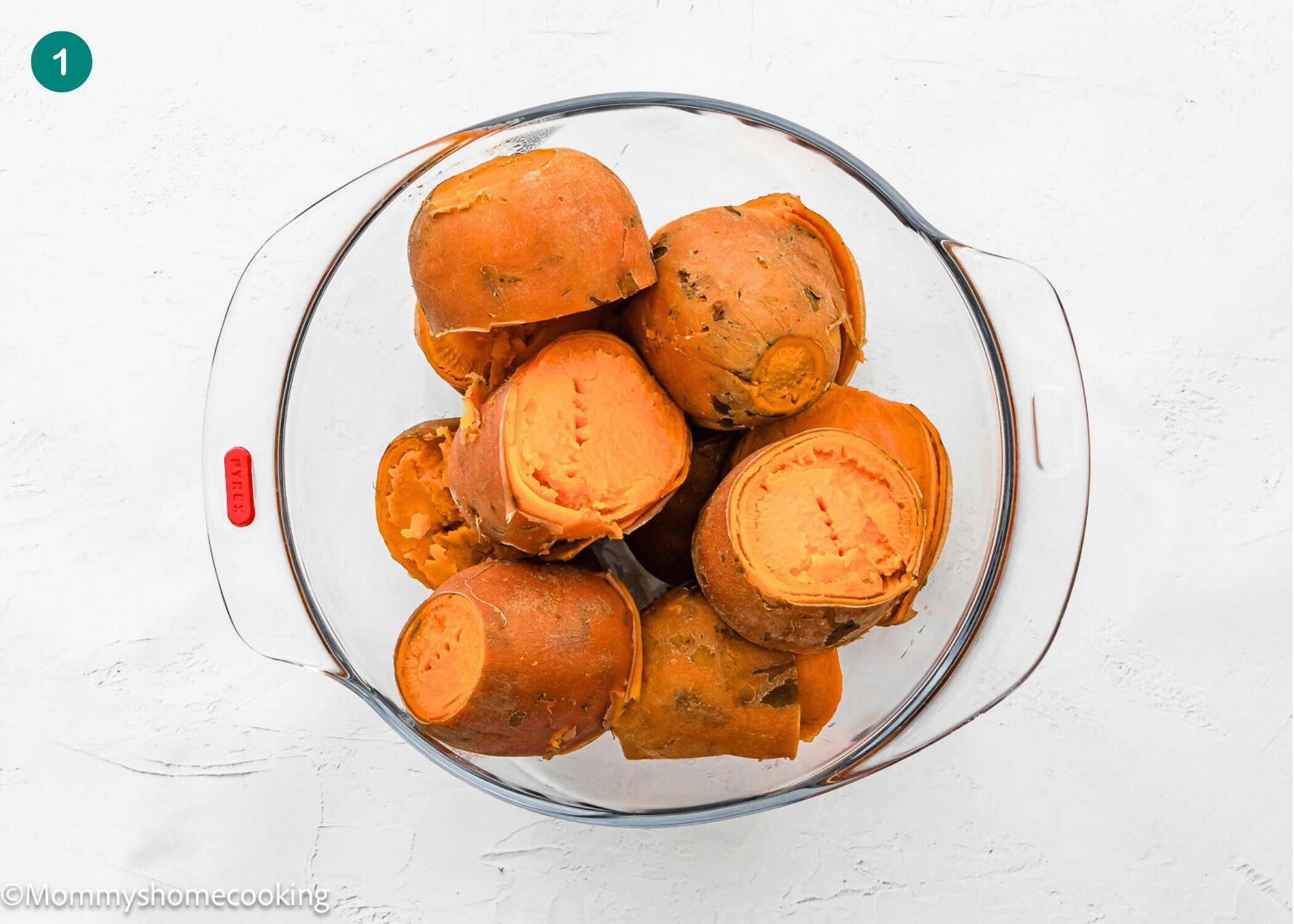 A glass bowl containing several cooked, peeled sweet potatoes for an Eggless Sweet Potato Casserole sits on a white surface.