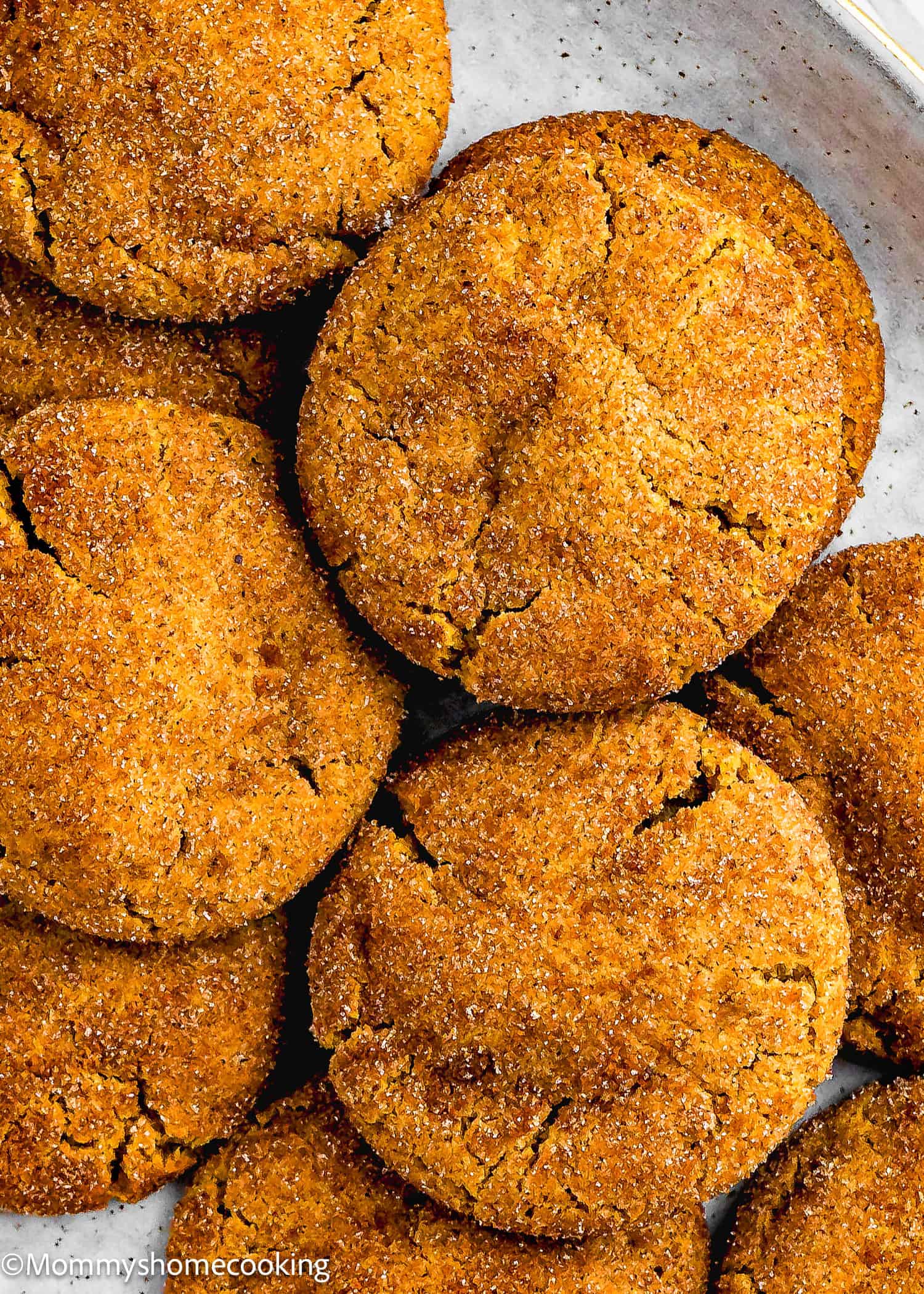 A close-up view of several golden-brown, sugar-coated Eggless Gingerbread Snickerdoodle cookies arranged on a plate.