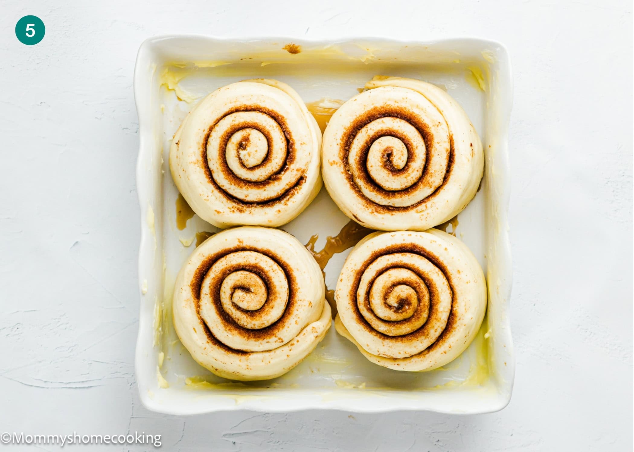 Four Overnight Cinnamon Rolls (Small Batch) arranged in a square baking dish, viewed from above on a white background.