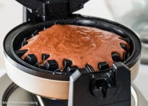 Eggless Chocolate Waffles batter spreads inside an open waffle maker, ready to be cooked.