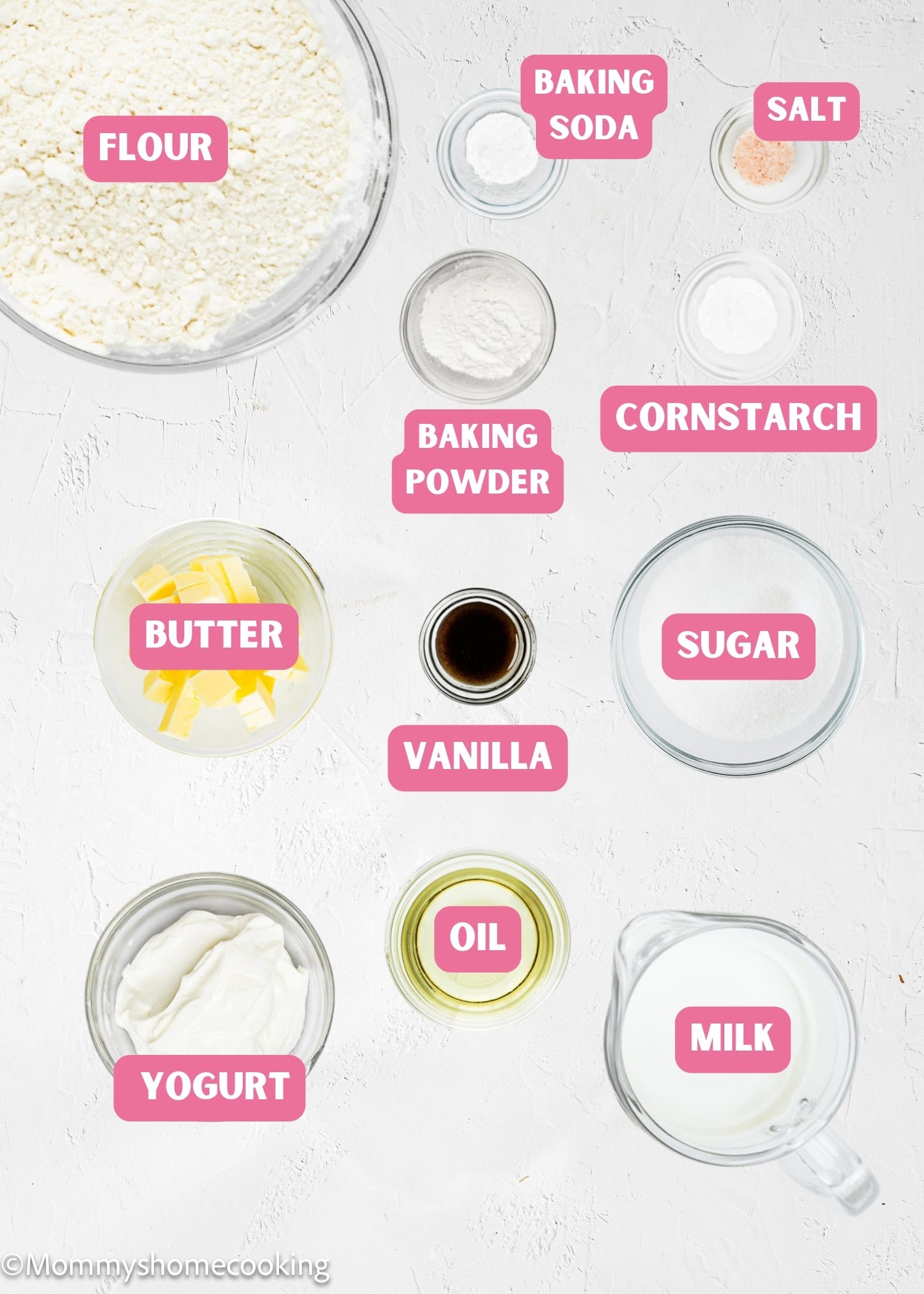 Top-down view of labeled baking ingredients for Eggless Yogurt Waffles in bowls and containers, including flour, baking soda, salt, baking powder, cornstarch, butter, vanilla, sugar, oil, milk, and Greek yogurt.