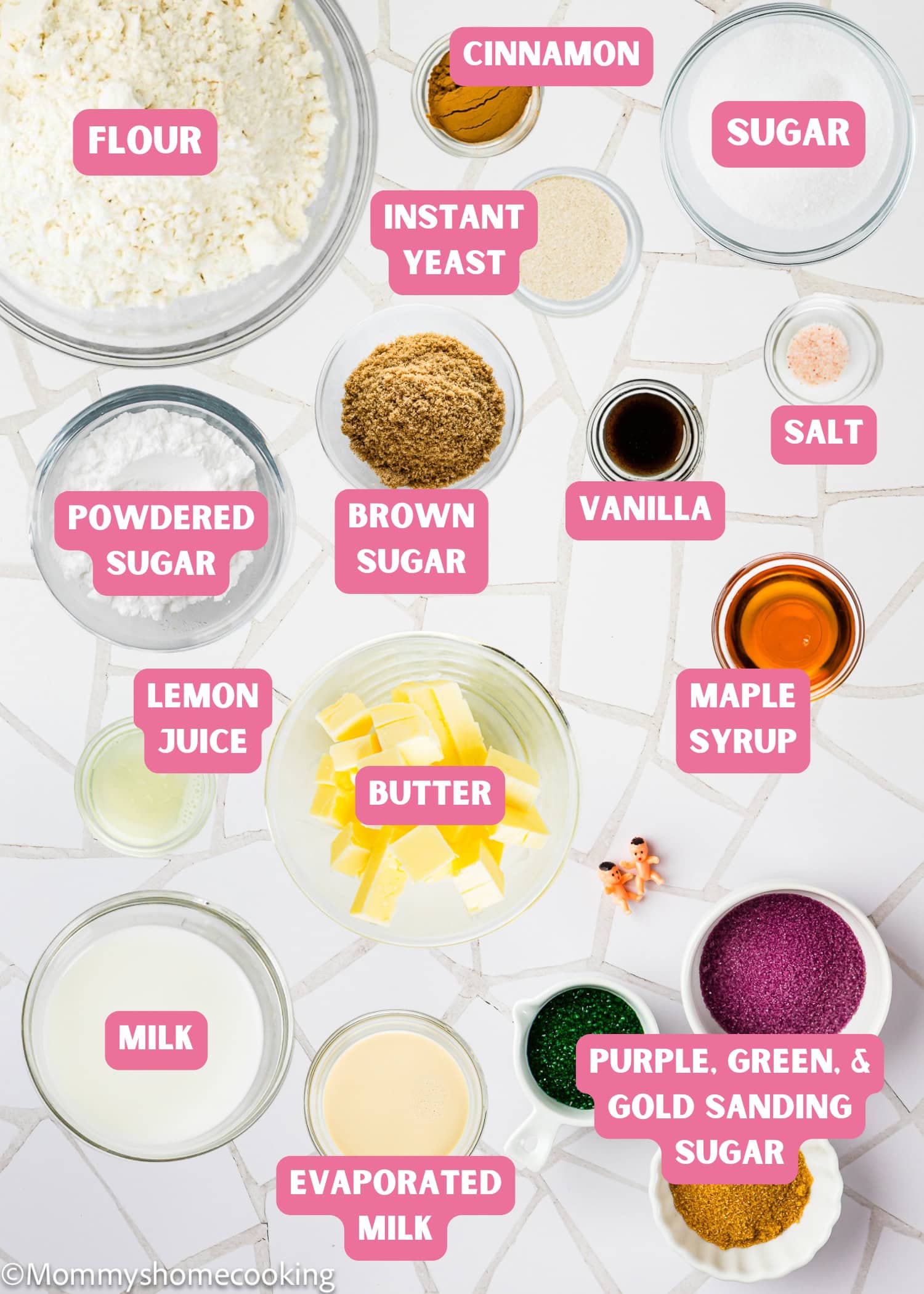 Ingredients for the Best Eggless Mardi Gras King Cake: flour, sugars, butter, milk, instant yeast, maple syrup, lemon juice, spices, and colored sanding sugars labeled in bowls.