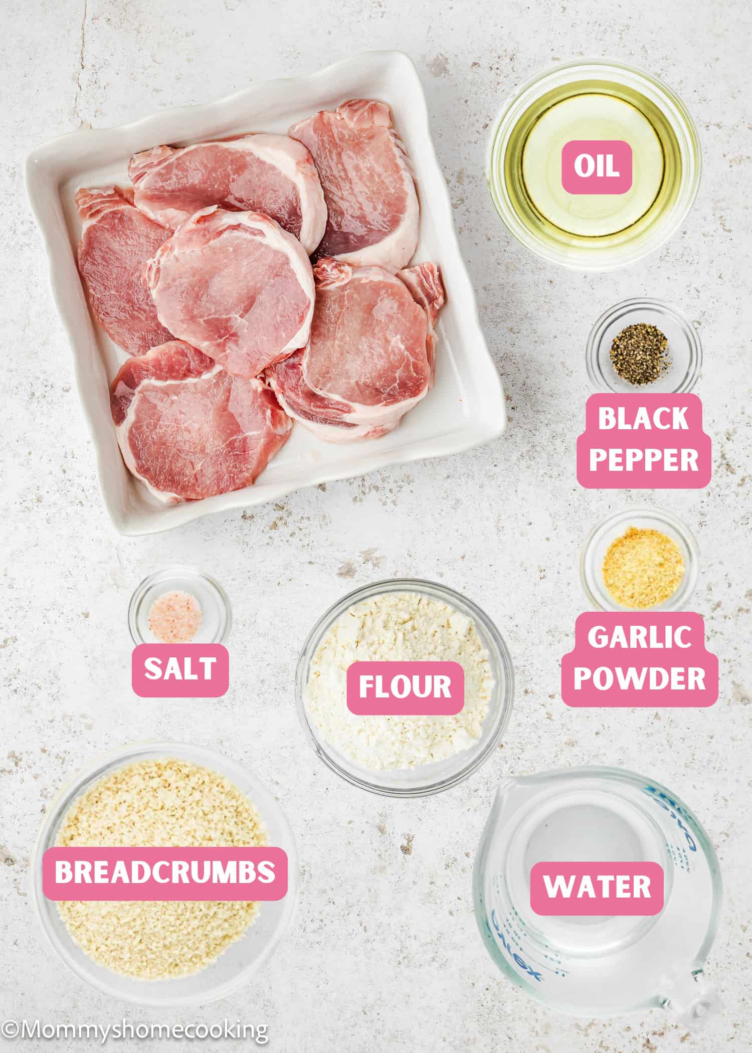 Raw pork chops in a white dish, surrounded by labeled bowls of oil, black pepper, garlic powder, salt, flour, breadcrumbs, and water—perfect for making Crispy Eggless Pork Schnitzel that's egg and dairy free.