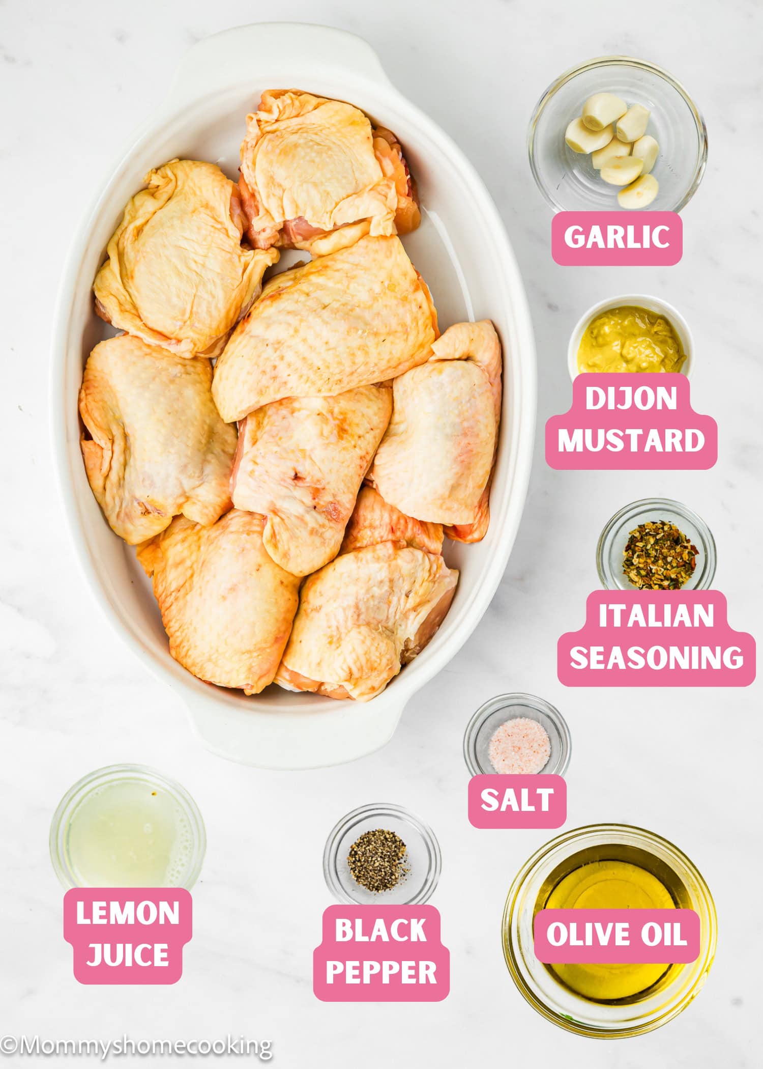 Raw chicken thighs in a baking dish are surrounded by small bowls of garlic, Dijon mustard, Italian seasoning, salt, olive oil, black pepper, and lemon juice—perfect for making Easy Baked Lemon Chicken Thighs.
