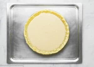 Eggless Buttermilk Pie with crimped edges filled with a pale custard mixture sits on a metal baking sheet.