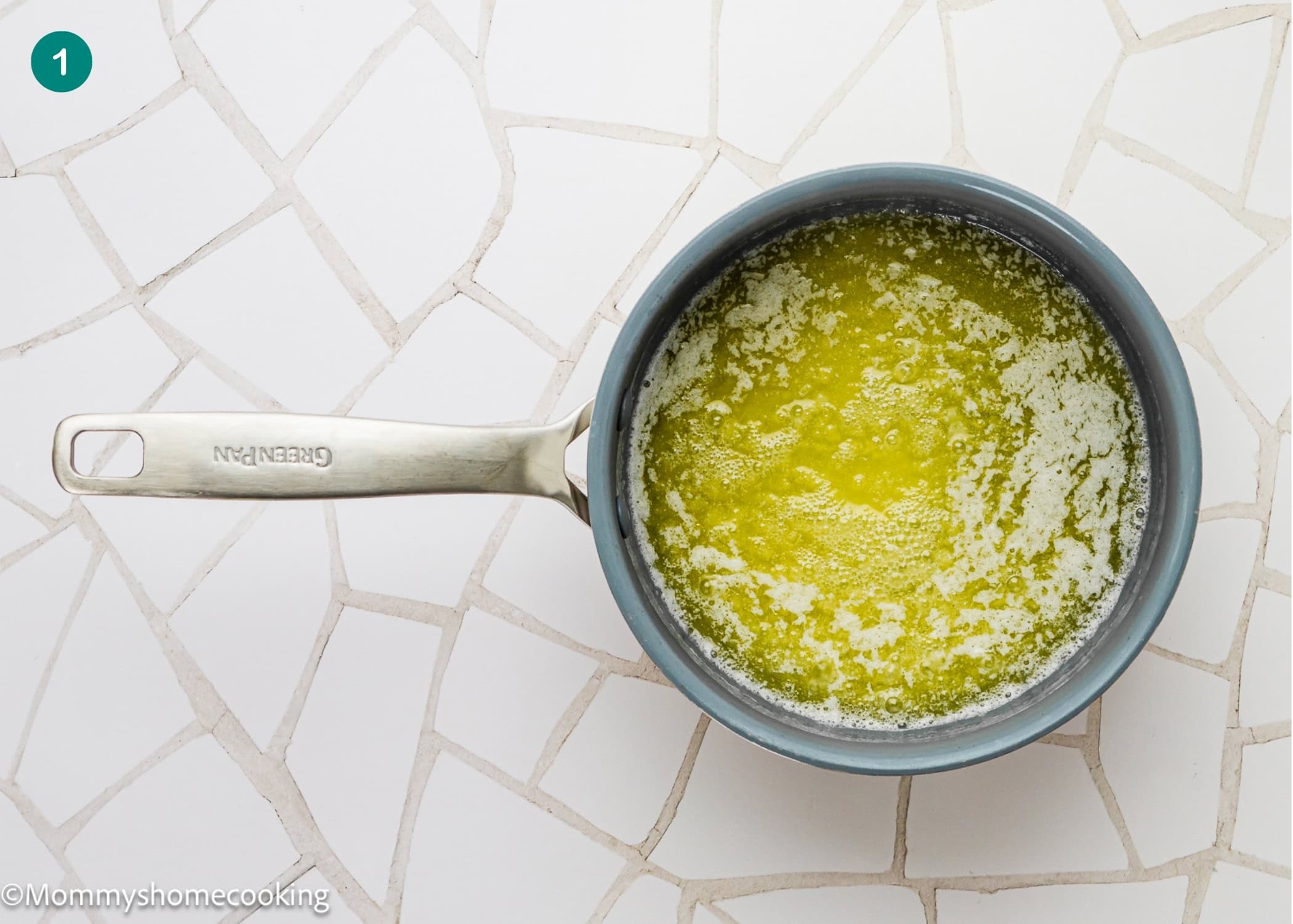 A saucepan with melted butter sits on a white tiled surface, ready to make an easy Béchamel sauce (classic white sauce recipe).