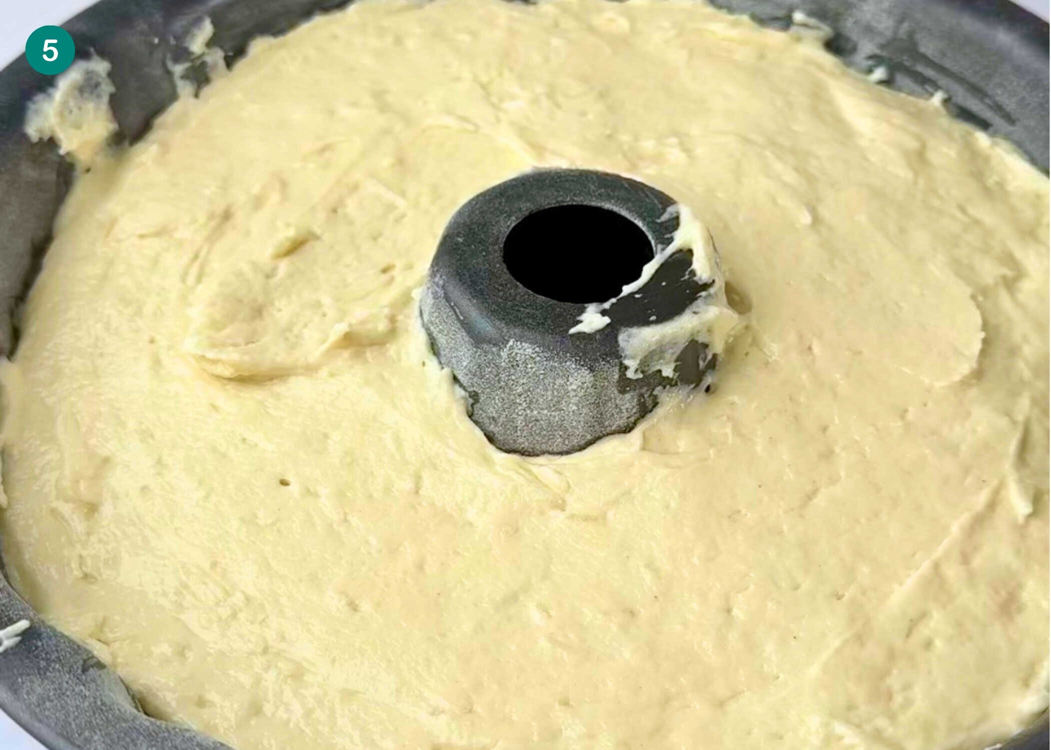 Eggless Coconut Bundt Cake batter is spread evenly in a greased bundt cake pan, ready to be baked.
