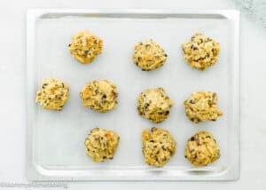 A baking sheet with ten unbaked Egg-Free S’mores Cookies dough balls on parchment paper.