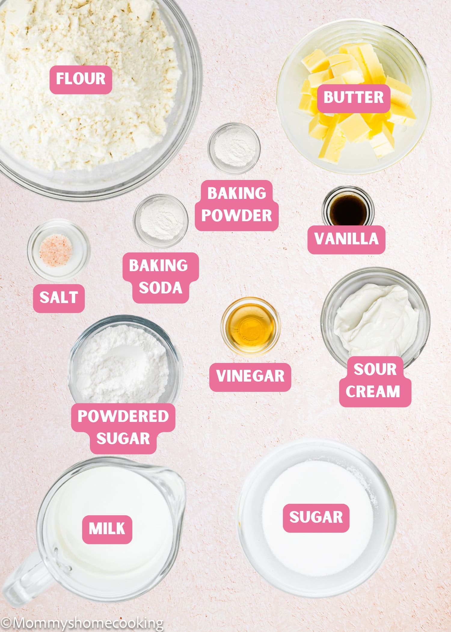 Top-down view of baking ingredients for an Eggless Pound Cake Loaf in bowls and cups, including flour, butter, baking powder, baking soda, salt, vanilla, vinegar, sour cream, powdered sugar, milk, and sugar.