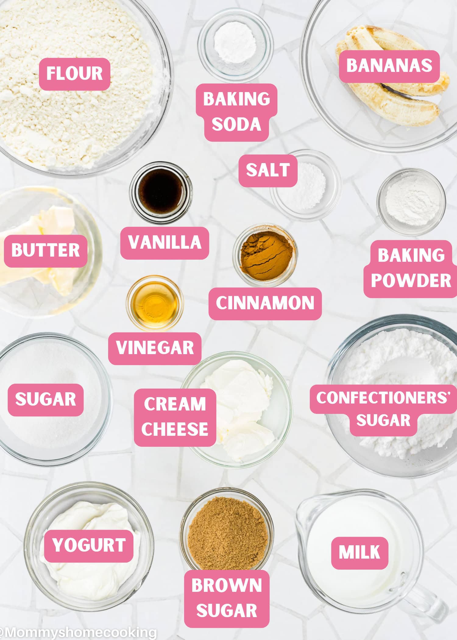 Top-down view of various labeled baking ingredients in bowls and plates for Eggless Banana Bars With Cream Cheese Frosting, including flour, bananas, sugar, butter, yogurt, cream cheese, spices, and leavening agents on a white surface.