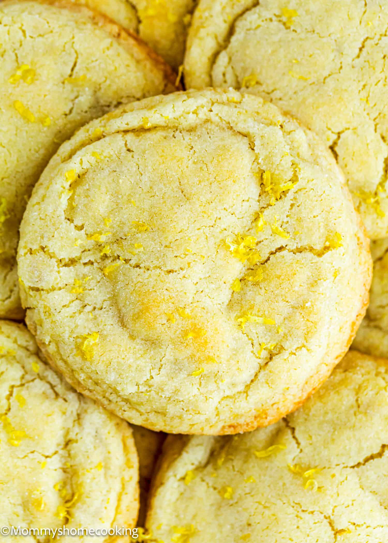 Close-up of several Eggless Lemon Sugar Cookies (Soft & Chewy) with visible cracks and bits of lemon zest on top.