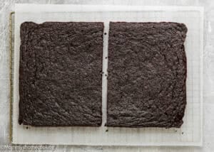 A large, rectangular chocolate cake cut in half on a cooling rack lined with parchment paper—perfect for making Eggless Brownie Ice Cream Sandwiches.