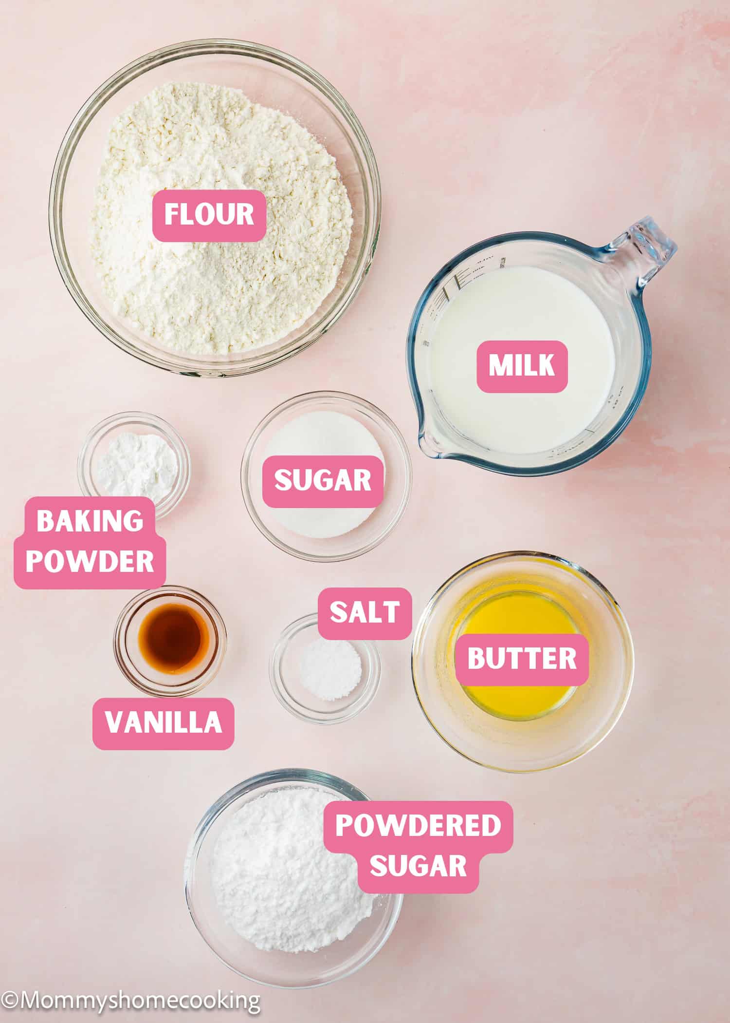 Top-down view of measured baking ingredients for an Eggless Funnel Cake Recipe in bowls and a pitcher on a pink surface, labeled as flour, milk, baking powder, sugar, salt, vanilla, butter, and powdered sugar.