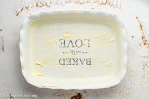 A rectangular ceramic baking dish greased with butter, showing the text “BAKED with LOVE” in reverse on the bottom—perfect for making Eggless Sticky Buns.
